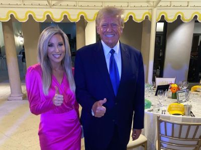 Jenn Pellegrino and Donald Trump are posing with their thumbs up.
